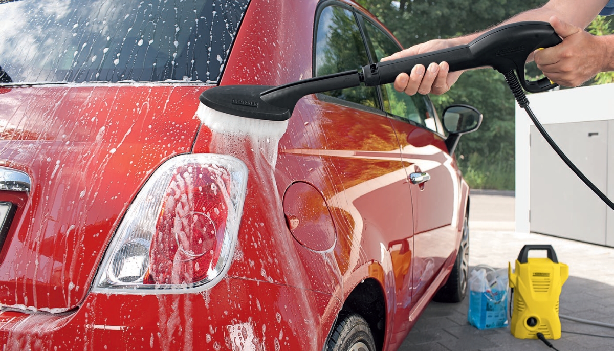 Myjka wysokociśnieniowa K 2 Car firmy Karcher. Myjka wysokociśnieniowa K 2 Car firmy Karcher. Mężczyzna myje samochod szczotką Soft clean z białym włosiem za pomocą myjki K 2 w zestawie Car.