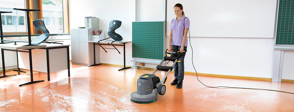 Profesjonalna szorowarka BDS 33/180 C Adv firmy Karcher Profesjonalne urządzenie do szorowania podłóg BDS 33/180 C Adv firmy Karcher. Kobieta szoruję podłogę w klasie. Podłoga wykonana z linoleum.