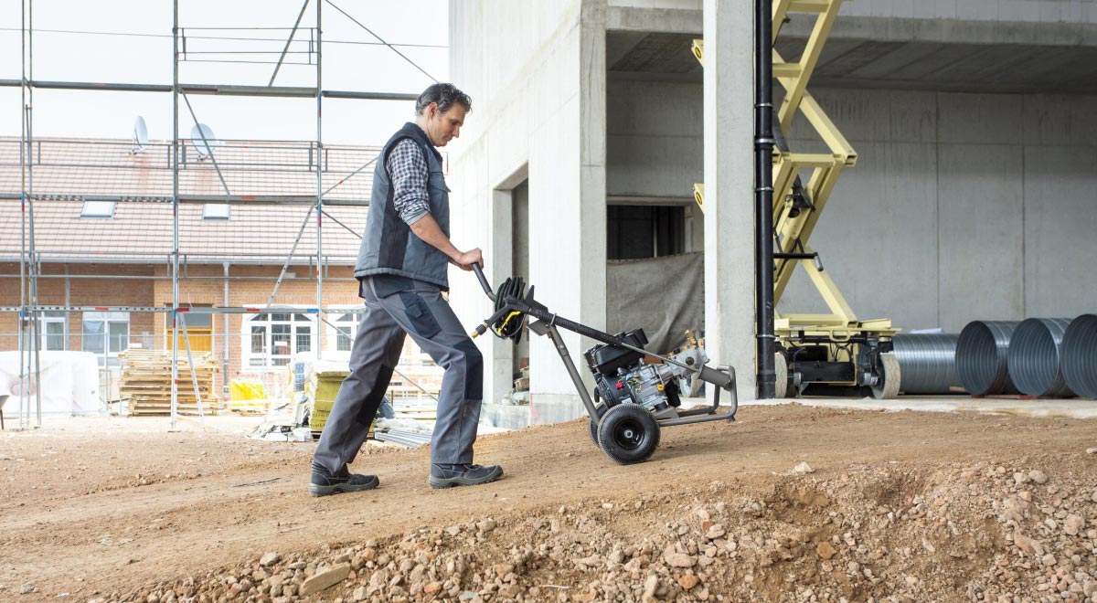 Profesjonalna myjka wysokociśnieniowa HD7/20 G Classic firmy Karcher z silnikiem spalinowym Profesjonalna myjka wysokociśnieniowa HD 8/23 G Classic firmy Karcher z silnikiem spalinowym podczas transportu myjki pod górkę.