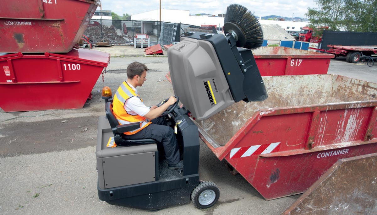 Profesjonalna, zamiatarka przemysłowa KM 130/300 R Bp firmy Karcher z napędem akumulatorowym. Profesjonalna, zamiatarka przemysłowa KM 130/300 R Bp firmy Karcher z napędem akumulatorowym. Mężczyzna opróżnia zbiornik na zanieczyszczenia za pomocą hydraulicznego podnoszenia zbiornika. Funkcja ta dostępna jest w przemysłowej zamiatarce KM 130/300 R Bp firmy Karcher.