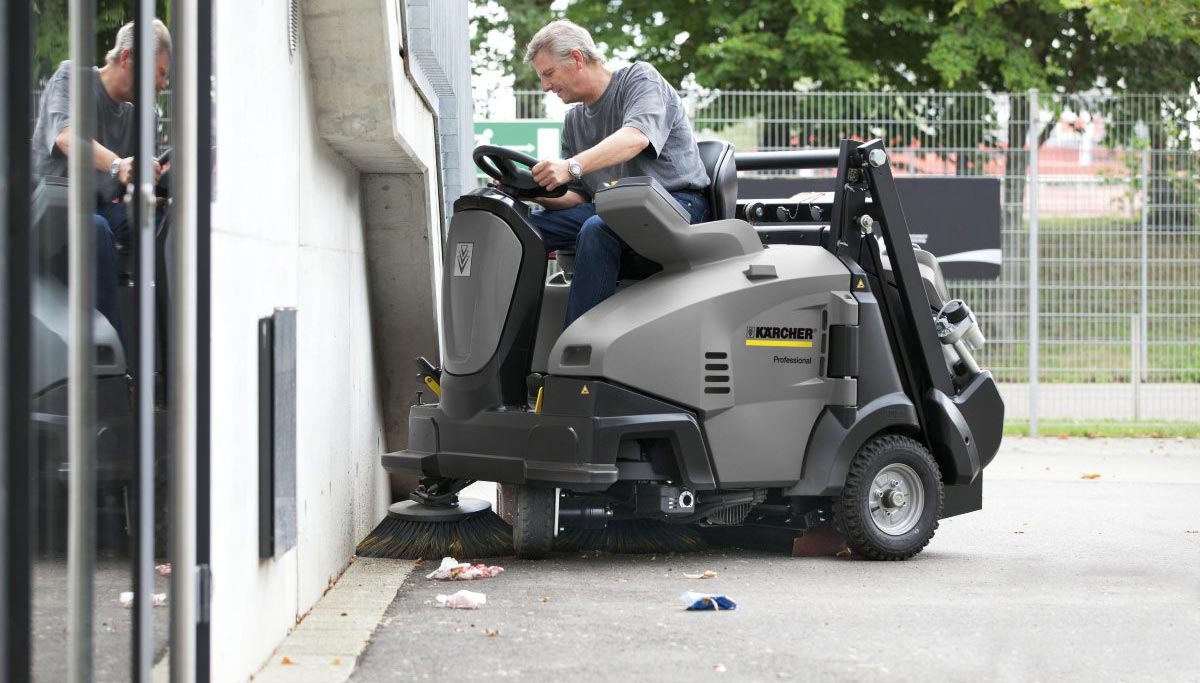 Przykład ilustrujący zamiatarkę podczas pracy Operator zamiata przy ścianie, wykorzystując nowoczesną zamiatarkę Karcher