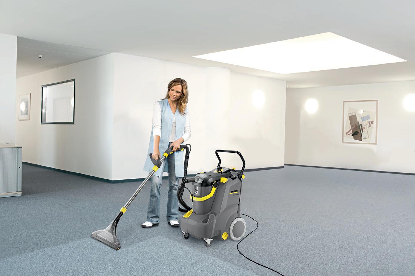 Profesjonalne urządzenie ekstrakcyjne Puzzi 30/4 E firmy Karcher Profesjonalne urządzenie ekstrakcyjne Puzzi 30/4 E firmy Karcher. Kobieta czyszcząca ekstrakcyjnie wykładzinę podłogową.