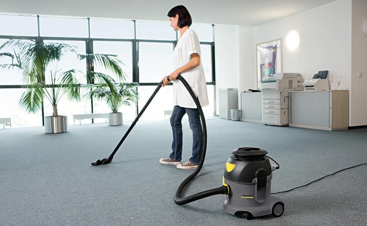 Profesjonalny odkurzacz jednofunkcyjny T 10/1 eco!efficiency firmy Karcher Profesjonalny odkurzacz jednofunkcyjny T 10/1 eco!efficiency firmy Karcher. Kobieta odkurzająca wykładzinę podłogową w pomieszczeniu biurowym.