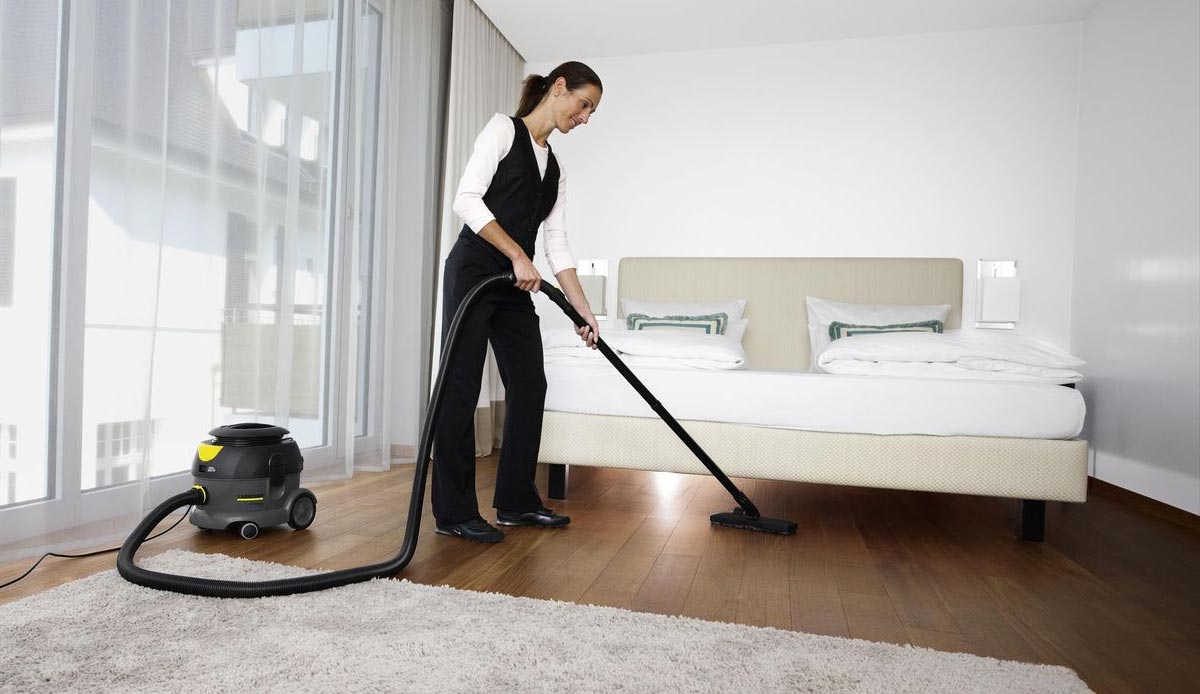 Profesjonalny odkurzacz jednofunkcyjny T 12/1 firmy Karcher Profesjonalny odkurzacz jednofunkcyjny T 12/1 firmy Karcher. Kobieta odkurzająca podłogę w pokoju hotelowym.