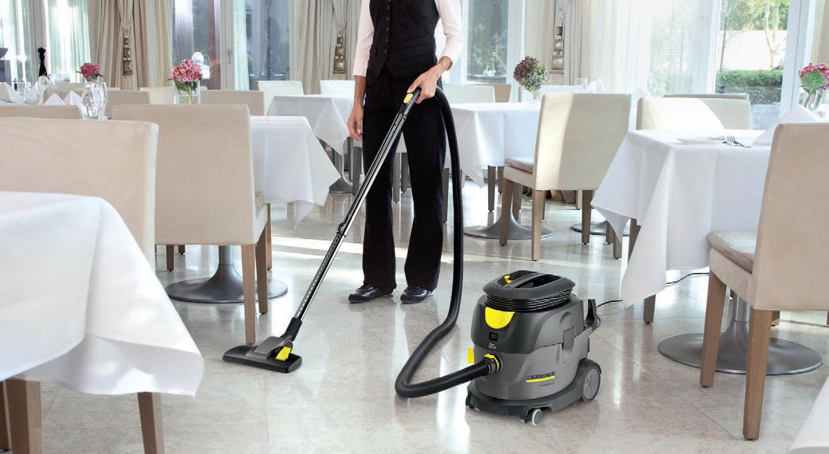 Profesjonalny odkurzacz jednofunkcyjny T 15/1 eco!efficiency firmy Karcher Profesjonalny odkurzacz jednofunkcyjny T 15/1 eco!efficiency firmy Karcher. Kobieta odkurzająca podłogę w sali restauracyjnej.