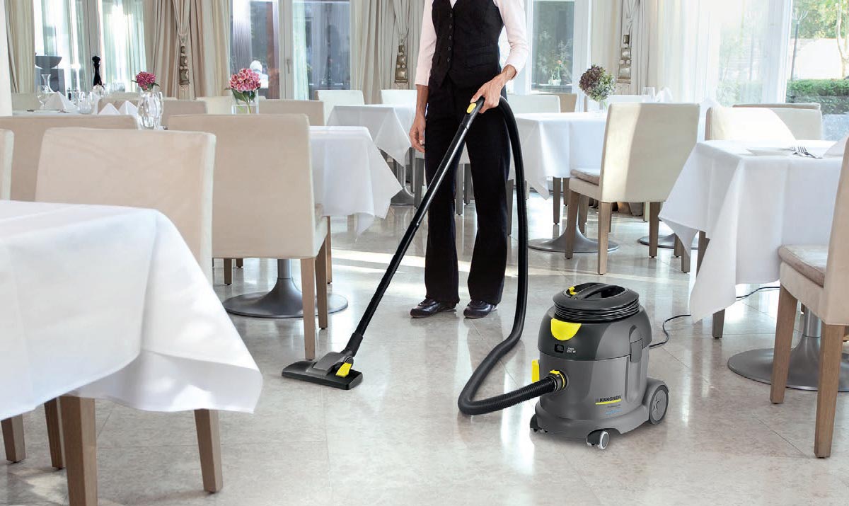 Profesjonalny odkurzacz jednofunkcyjny T 17/1 eco!efficiency firmy Karcher Profesjonalny odkurzacz jednofunkcyjny T 17/1 eco!efficiency firmy Karcher. Kobieta odkurzająca podłogę w sali restauracyjnej.